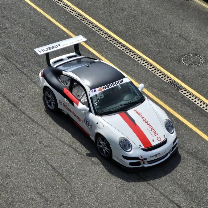 Weißes Rennauto mit roter Schneeberger Beschriftung auf einer Rennstrecke, aufgenommen aus erhöhter Perspektive.
