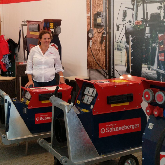 Messestand mit zwei rot-blauen Stromverteilern; eine Person steht dahinter und präsentiert die Geräte.