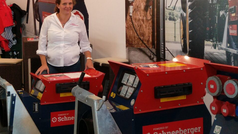 Messestand mit zwei rot-blauen Stromverteilern; eine Person steht dahinter und präsentiert die Geräte.