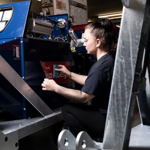 Mitarbeiterin bringt in der Montagehalle einen Schneeberger-Aufkleber auf das Gehäuse eines Zapfwellengenerators auf.