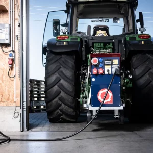 Traktor steht rückwärts in der Halle, ein Schneeberger Zapfwellengenerator ist angeschlossen und versorgt das Gebäude mit Strom.