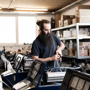 Monteur verdrahtet die elektrische Steuerung mehrerer Schneeberger Zapfwellengeneratoren in der Werkstatt